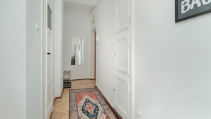 A hallway with white walls, a patterned rug, and a door with a mirror.