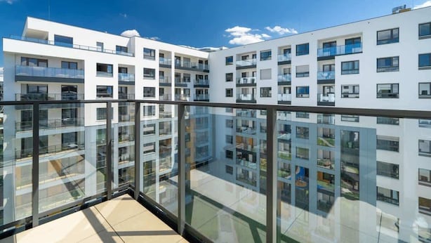 Un edificio de apartamentos moderno con varios balcones y ventanas grandes.