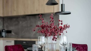 Una mesa de comedor dispuesta con platos, vasos y jarrones con flores rojas.