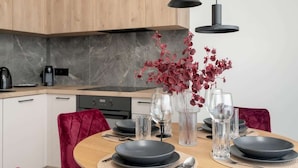 Una cocina moderna con armarios de madera, salpicadero de mármol y una zona de comedor con una mesa redonda dispuesta para cuatro personas.