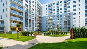 Un edificio residencial de varios pisos con balcones, un parque infantil y un jardín bien cuidado.