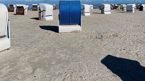 A beach with rows of white beach huts, some with blue tarps, under a clear blue sky. - Design Apartment in Carolinensiel (Wittmund)