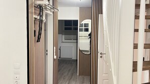 A narrow hallway with wooden paneling on the walls, a white door on the right, and a white radiator in the background. - Design Apartment in Carolinensiel (Wittmund)