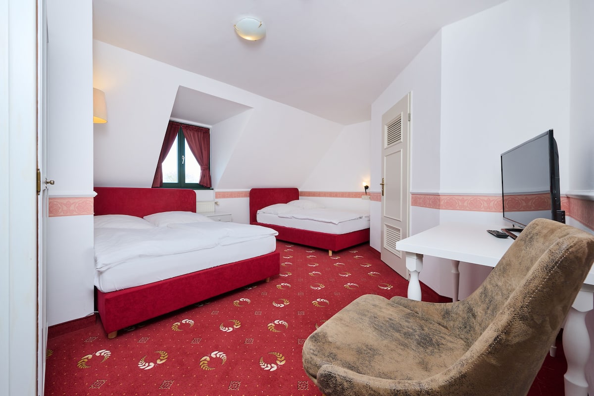 Une chambre d’hôtel avec deux lits, un bureau, une chaise et un téléviseur.