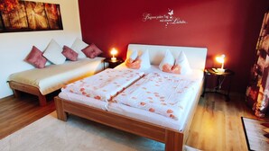 A bedroom with a wooden bed, a red accent wall, and a ceiling with exposed beams and lighting.