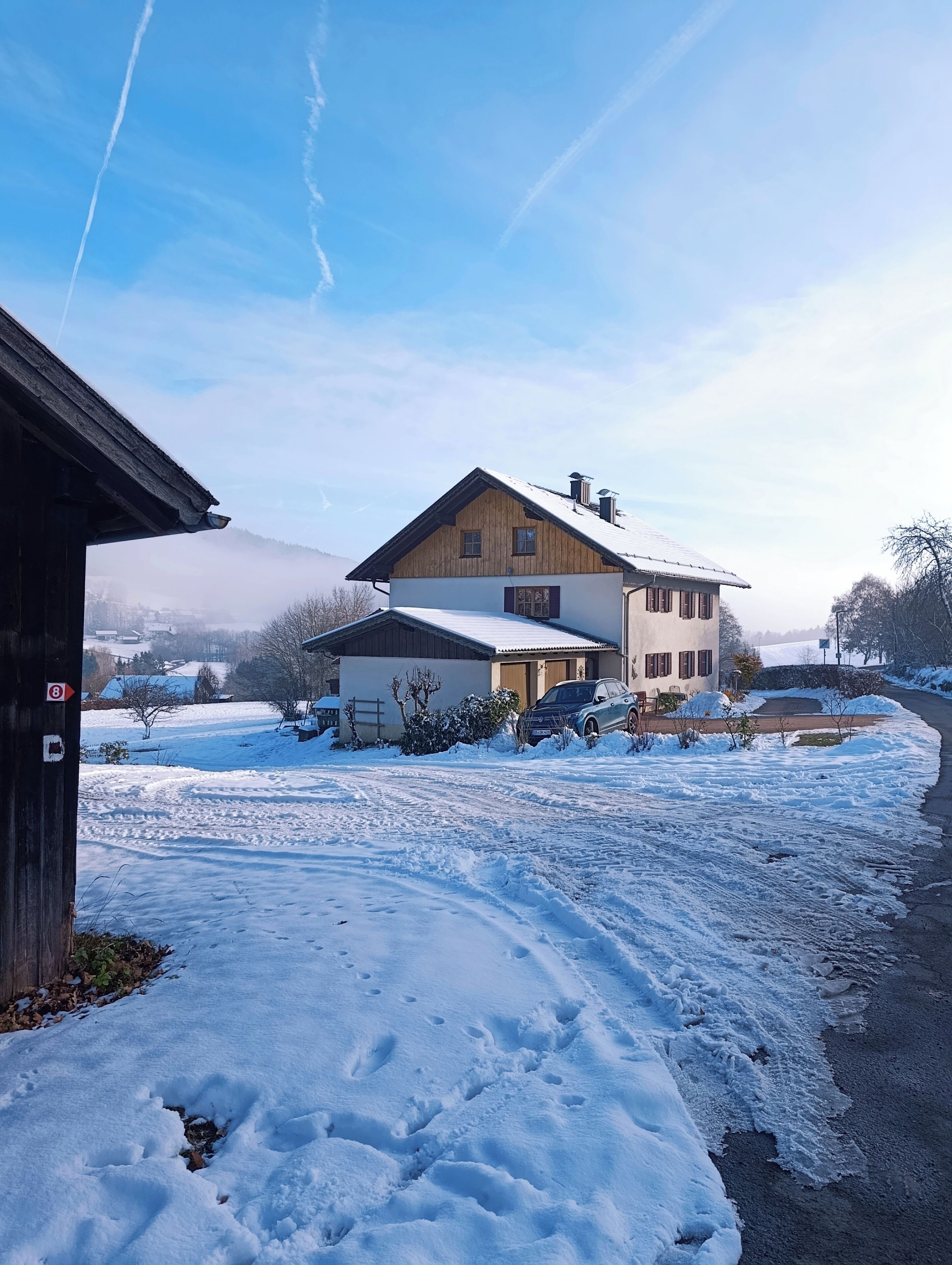 Une maison à deux étages avec une cour enneigée et un ciel dégagé.