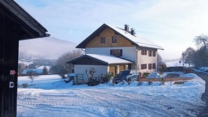A two-story house with a snow-covered yard and a clear sky.