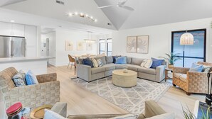 A spacious living area with a large sectional sofa, a round coffee table, and a dining area with a glass-top table.