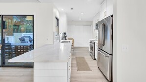 A modern kitchen with white cabinetry, stainless steel appliances, and a large island.
