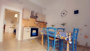 A kitchen with a dining table, chairs, and a wall clock.