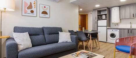 Una sala de estar moderna con un sofá gris, una mesa de centro y una zona de comedor con sillas.