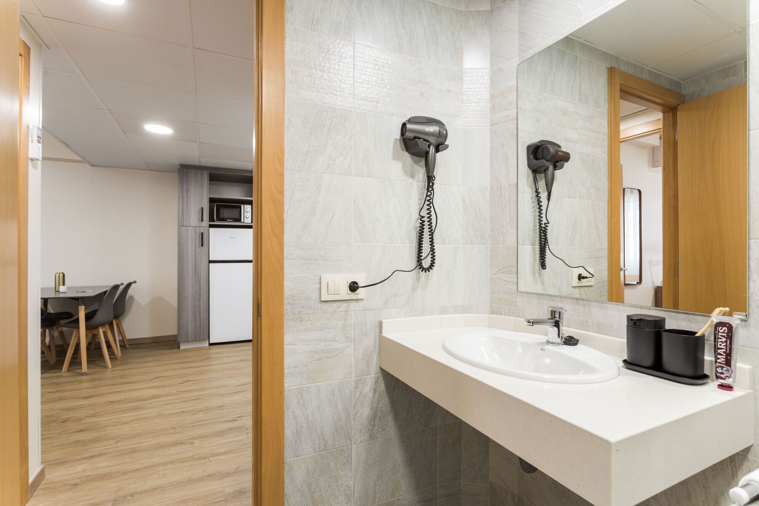 Een moderne badkamer met een wastafel, spiegel en haardroger.
