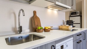 Una cocina moderna con un lavamanos de acero inoxidable, tabla de cortar de madera y tazones con fruta.