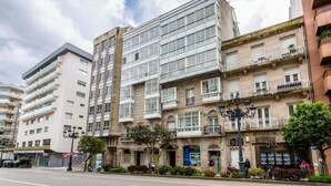 Un edificio de varios pisos con una mezcla de estilos arquitectónicos, incluyendo un moderno frente de cristal y balcones tradicionales.