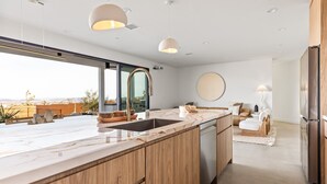 Eine moderne Küche mit einer großen Kochinsel, Holzschränken und Blick ins Freie.