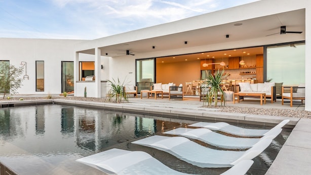 Ein modernes Haus mit Swimmingpool, Außenbereich zum Sitzen und einer großen, offenen Küche.