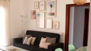 A living room with a black sofa, green chairs, a glass dining table, and a woven pendant light. - Tranquilidad, Naturaleza y Mar. Tu Refugio (L'Eucaliptus)