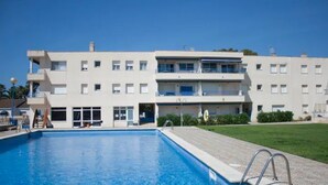 A modern building with a swimming pool, balconies, and a well-maintained lawn. - Tranquilidad, Naturaleza y Mar. Tu Refugio (L'Eucaliptus)