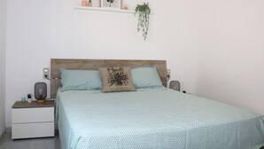 A bedroom with a bed, nightstands, a wall-mounted shelf with plants, and a hanging plant. - Tranquilidad, Naturaleza y Mar. Tu Refugio (L'Eucaliptus)