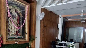Un espace d’accueil avec un comptoir de réception en bois, un lustre et une statue religieuse encadrée.