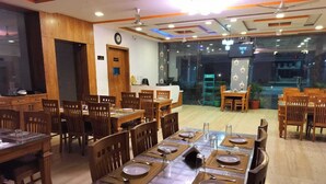 Un restaurant doté de nombreuses tables et chaises en bois, d’un comptoir d’accueil et d’un mur en verre donnant sur l’extérieur.