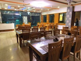 Un restaurante con varias mesas y sillas de madera, una barra y un amplio ventanal.