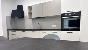 Una cocina moderna con armarios blancos, horno negro y pileta de acero inoxidable.
