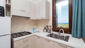 A modern kitchen with a gas stove, stainless steel sink, and a window with a view. - Cozy home in Marina di Modica with house sea view (Marina di Modica)
