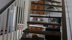 Eine Wendeltreppe mit Holzhinweisstufen und weißen Geländern führt zu einer erhöhten Ebene mit Schränken und einem Fenster.