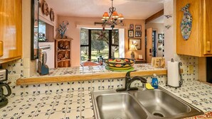 A kitchen with a double sink, wooden cabinets, a decorative bowl on the counter, and a chandelier.