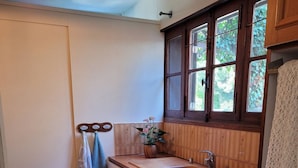 Een kleine keuken met een houten aanrecht, een spoelbak en een raam met uitzicht op groen.
