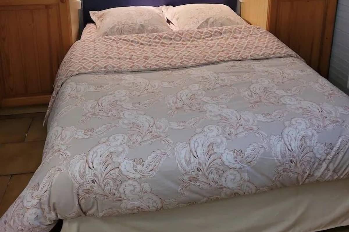 Ein Schlafzimmer mit Bett, Holzschrank und einem Kopfteil mit Beleuchtung.