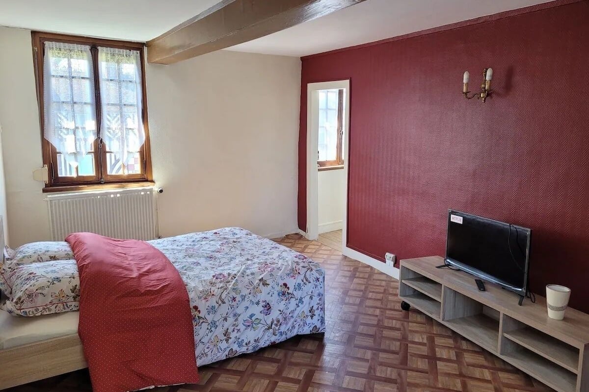 Ein Schlafzimmer mit einem Bett, einem Fernseher auf einem Schrank und einer Heizung.