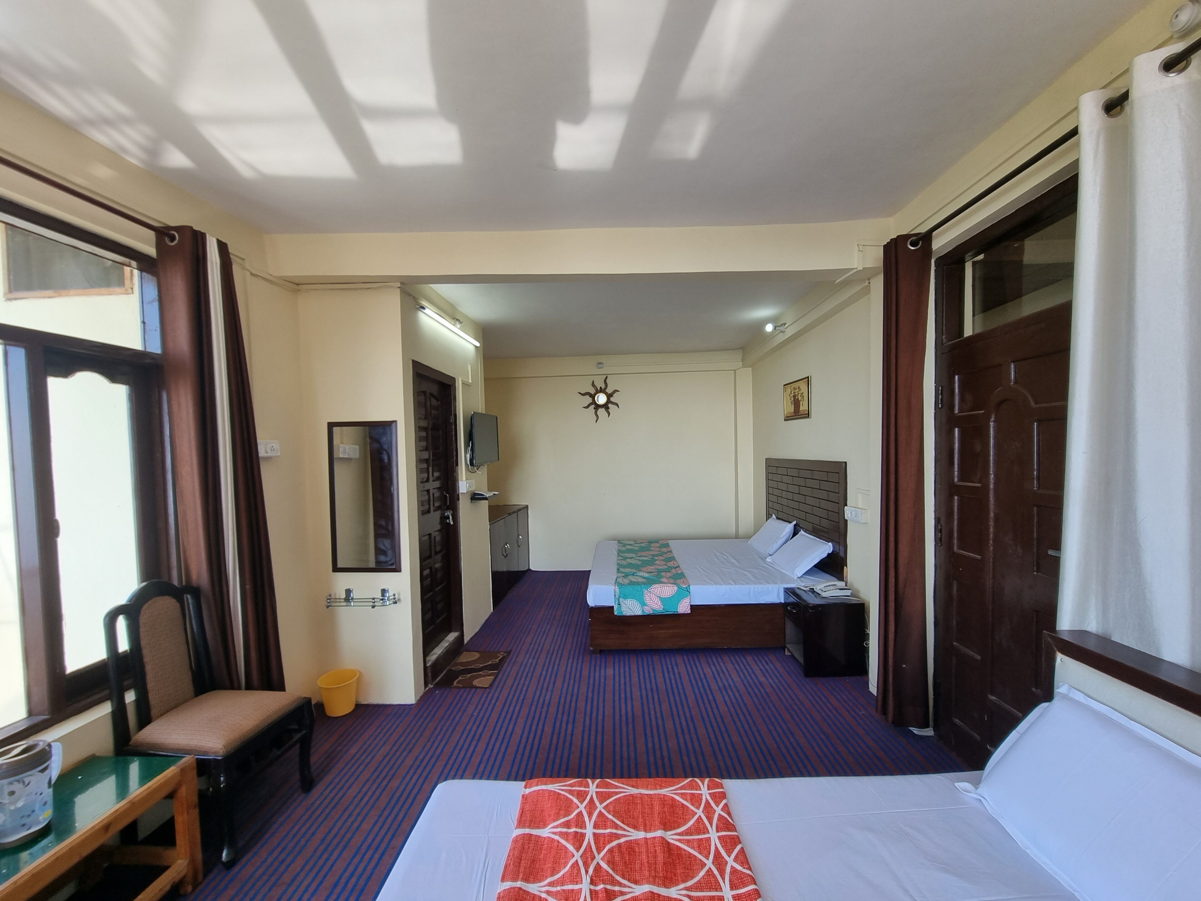 A hotel room with two beds, a desk, a chair, a television, and a small table.