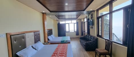 Habitación con dos camas, un sofá y una silla, con ventanas amplias que ofrecen una vista.