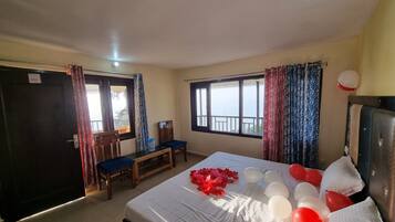 A hotel room with a bed, a desk, and a chair. There are curtains on the windows, and a balloon is visible on the wall.