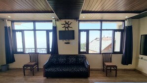 A room with a sofa, two chairs, a TV, and large windows with a view. - Smart Hill Kalatop (Dalhousie)