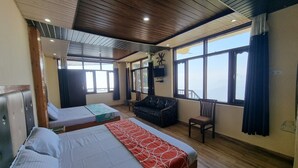 A hotel room with two beds, a sofa, a TV, and large windows offering a view. - Smart Hill Kalatop (Dalhousie)