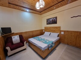 Un dormitorio con una cama de tablero de madera, un sofá, un televisor y un cuadro en la pared.