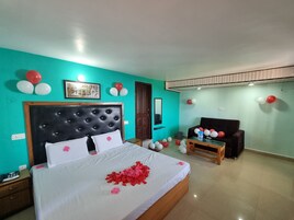 A bedroom with a large bed, a wooden nightstand, a wooden bench, and a small table. There are balloons on the walls and a picture frame on the wall.