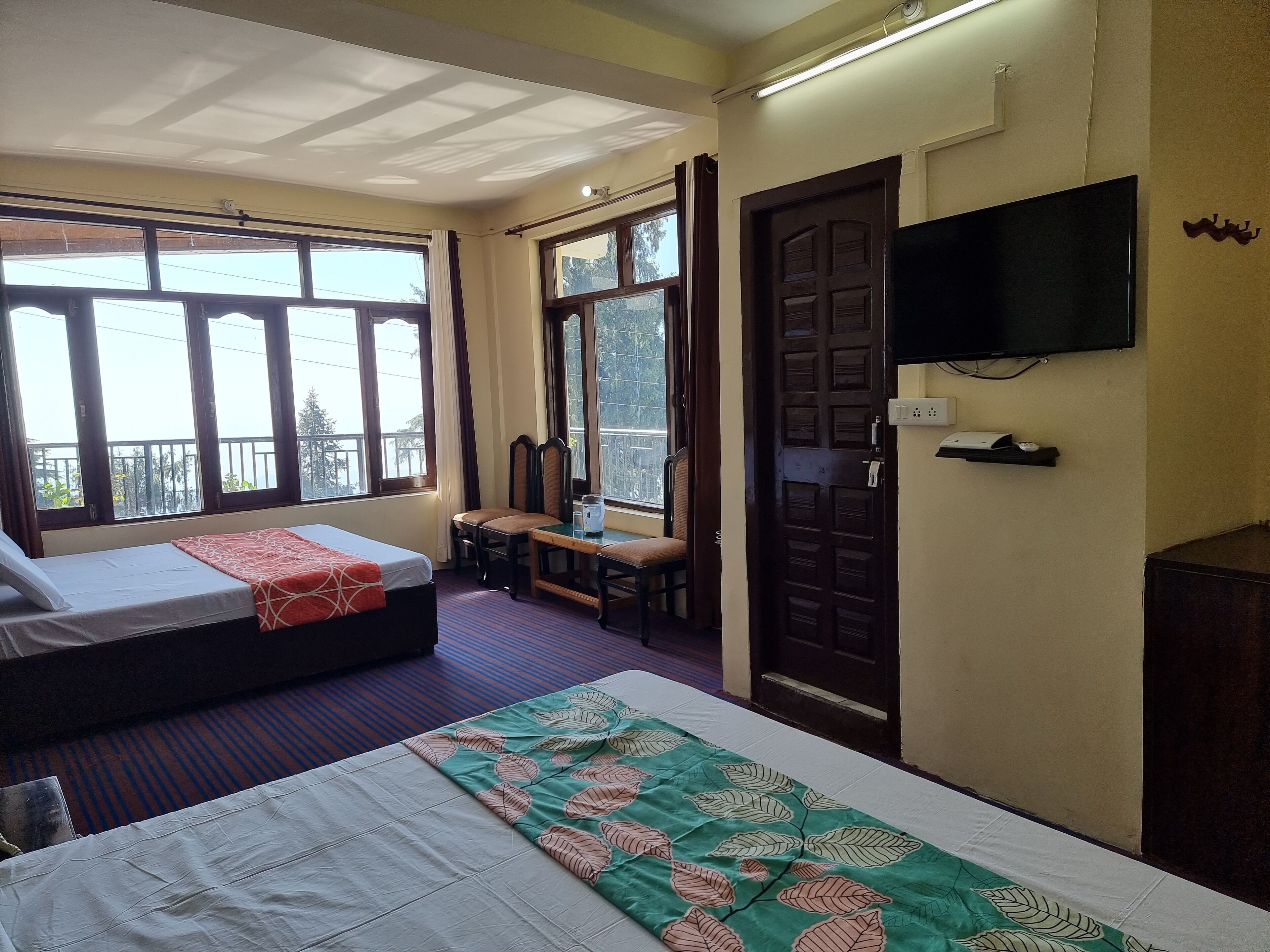 Une chambre d’hôtel avec deux lits, une télévision et un balcon donnant sur l’extérieur.