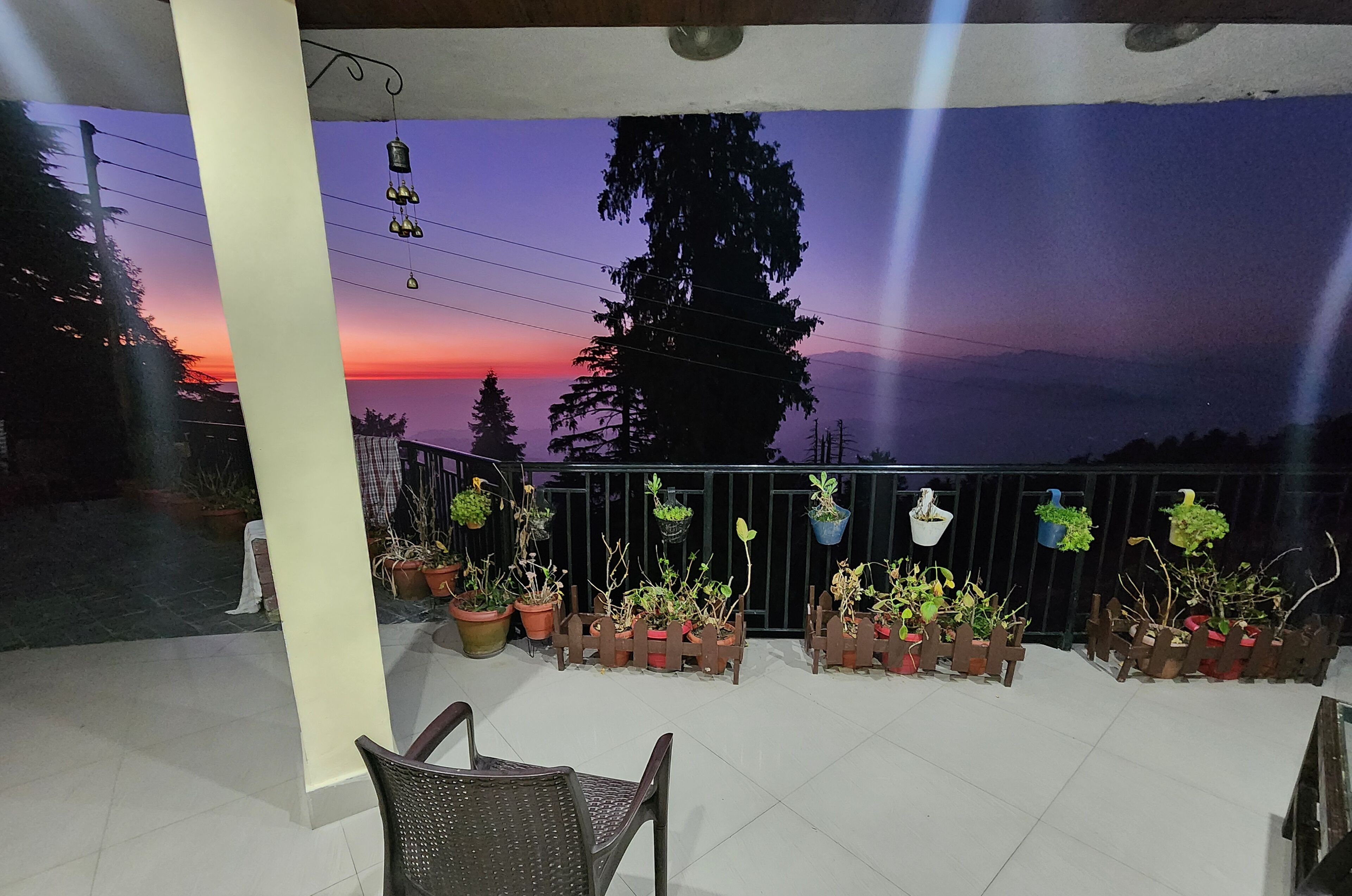 Un balcon agrémenté de plantes en pot, une chaise et une vue imprenable sur le coucher de soleil.