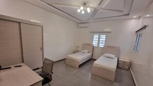 Een slaapkamer met twee éénpersoonsbedden, een bureau en een stoel.