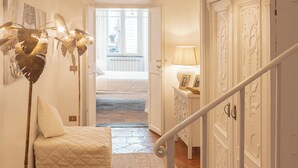 A hallway with a white bed, a floor lamp, and a cabinet. - Campo Viola 10 people (Rome)