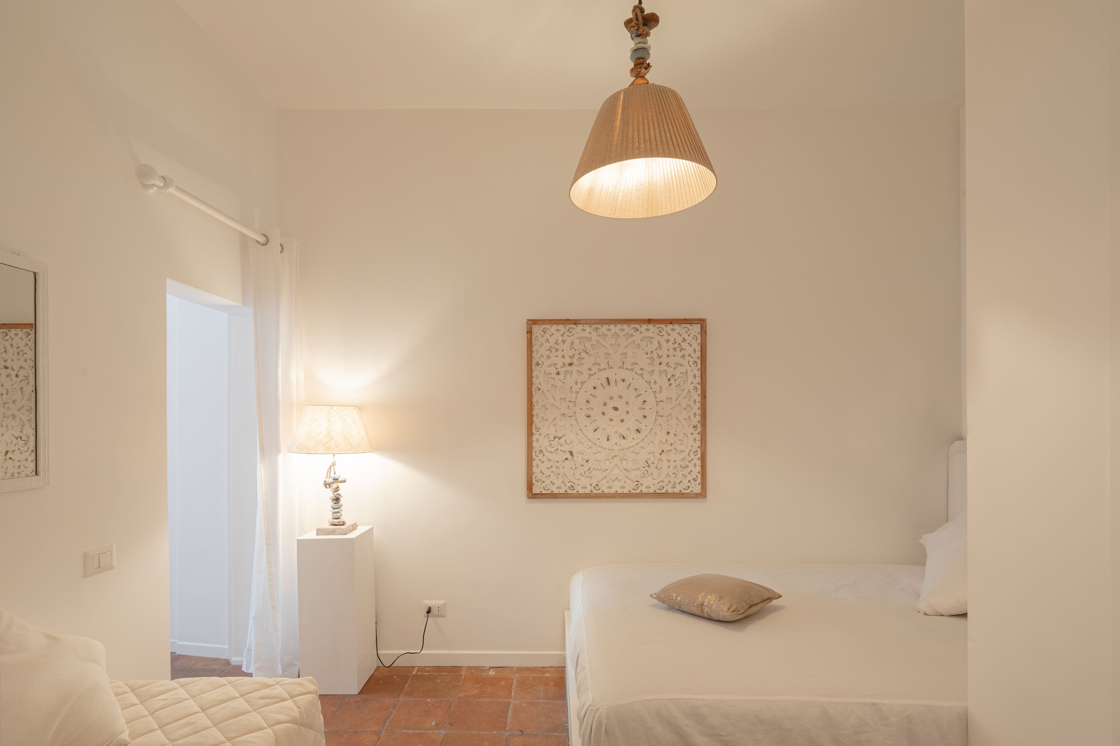 Ein Schlafzimmer mit einem Bett, einem Nachttisch mit Lampe, einem Wandbild und einer Deckenleuchte.