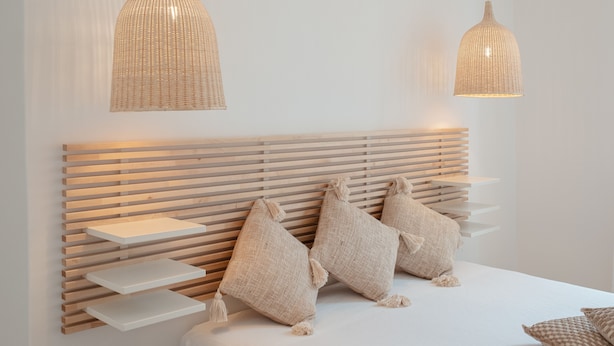 A modern bedroom with a wooden slatted headboard, two hanging woven light fixtures, and three textured pillows. - Campo Viola 10 people (Rome)