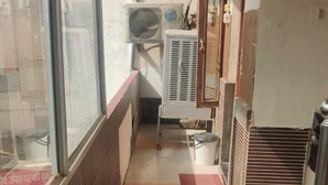 Un pasillo estrecho con una ventana a la izquierda, unidades de aire acondicionado y una puerta a la derecha.