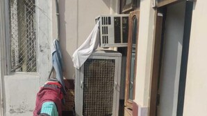 Un pasillo estrecho con una cama, una alfombra pequeña, una ventana y un equipo de aire acondicionado.
