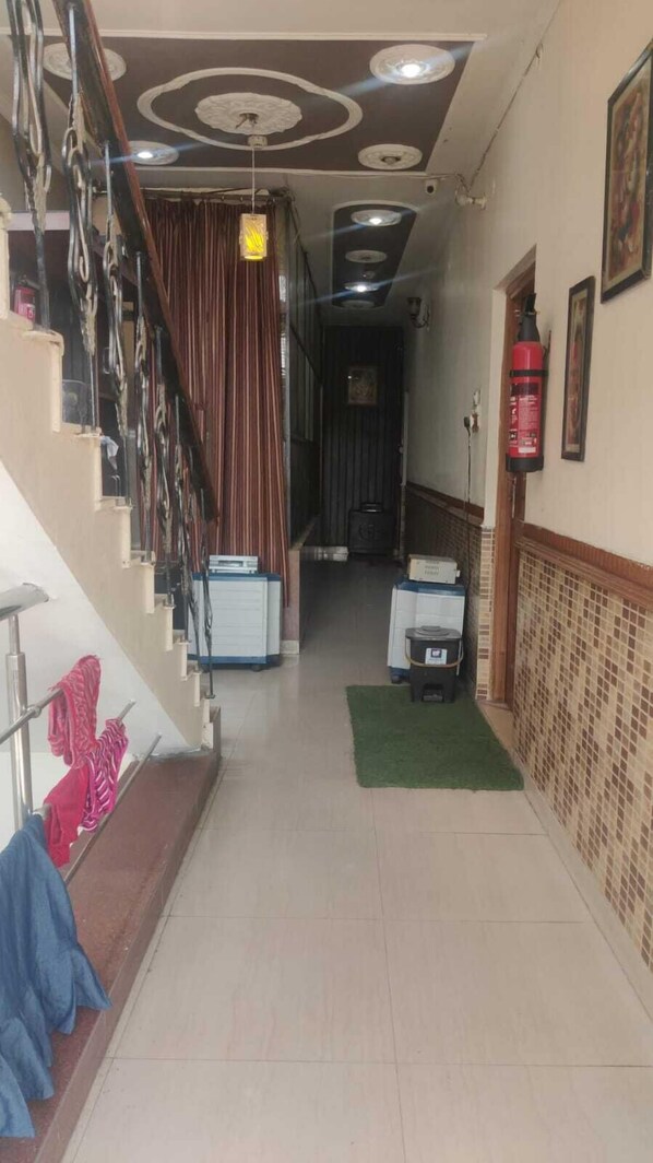 A hallway with a staircase, a fire extinguisher, and a green mat on the floor.