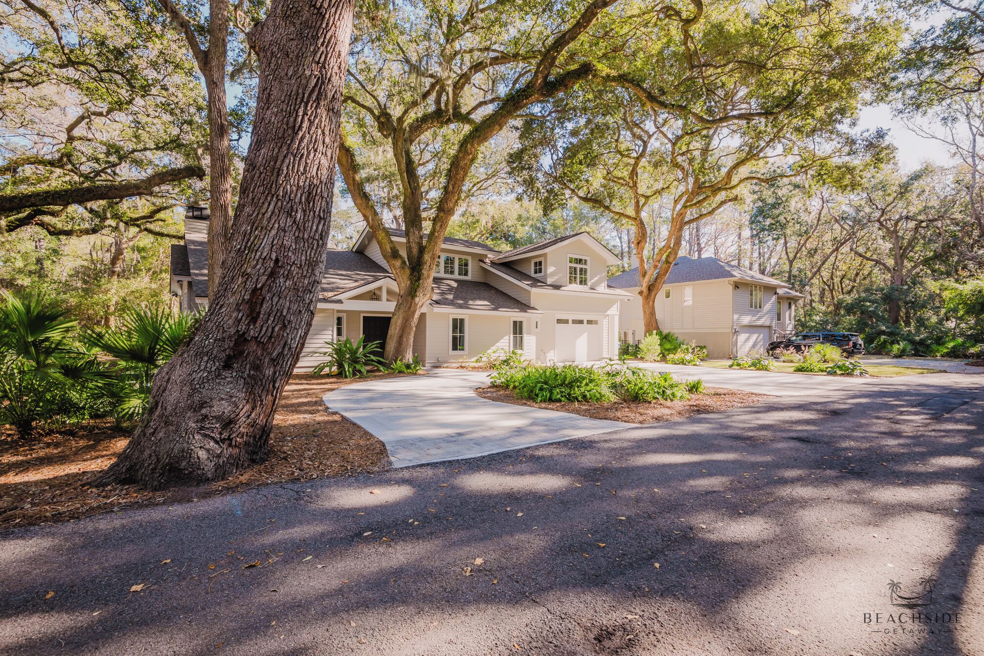 A two-story house with a garage, surrounded by mature trees and a well-maintained lawn.